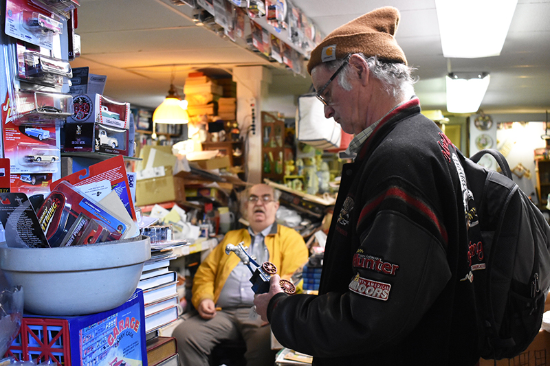 Dale Hadler holds an item of interest he found in Hunt’s antique shop and discusses with the shop owner what year the item might have been made.